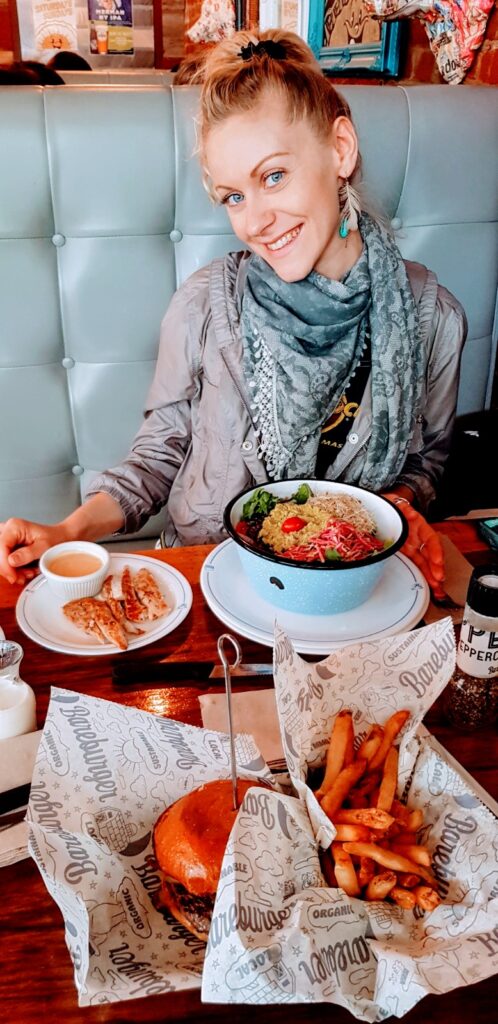 Pranzo vario a Brooklyn con insalata di quinoa, pollo speziato, hamburger accompagnato da patate fritte