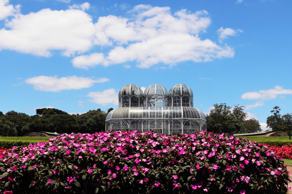 Il Giardino Botanico a Curitiba in Brasile circondato da prato verde e fiori in una giornata di sole.